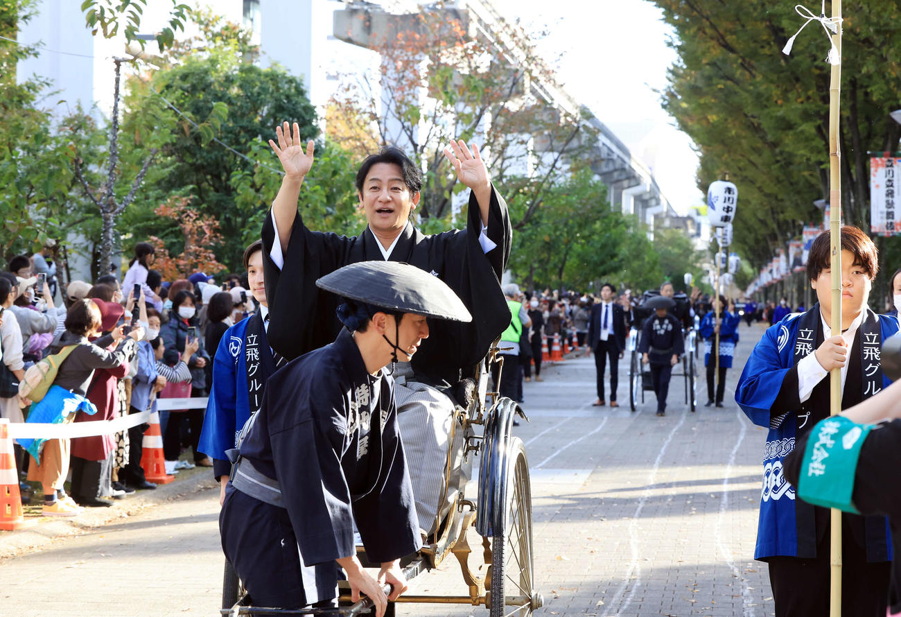 「立川立飛歌舞伎特別公演　お練り」で、人力車からファンに手を振る片岡愛之助。右後方には市川中車（撮影・浅見桂子）