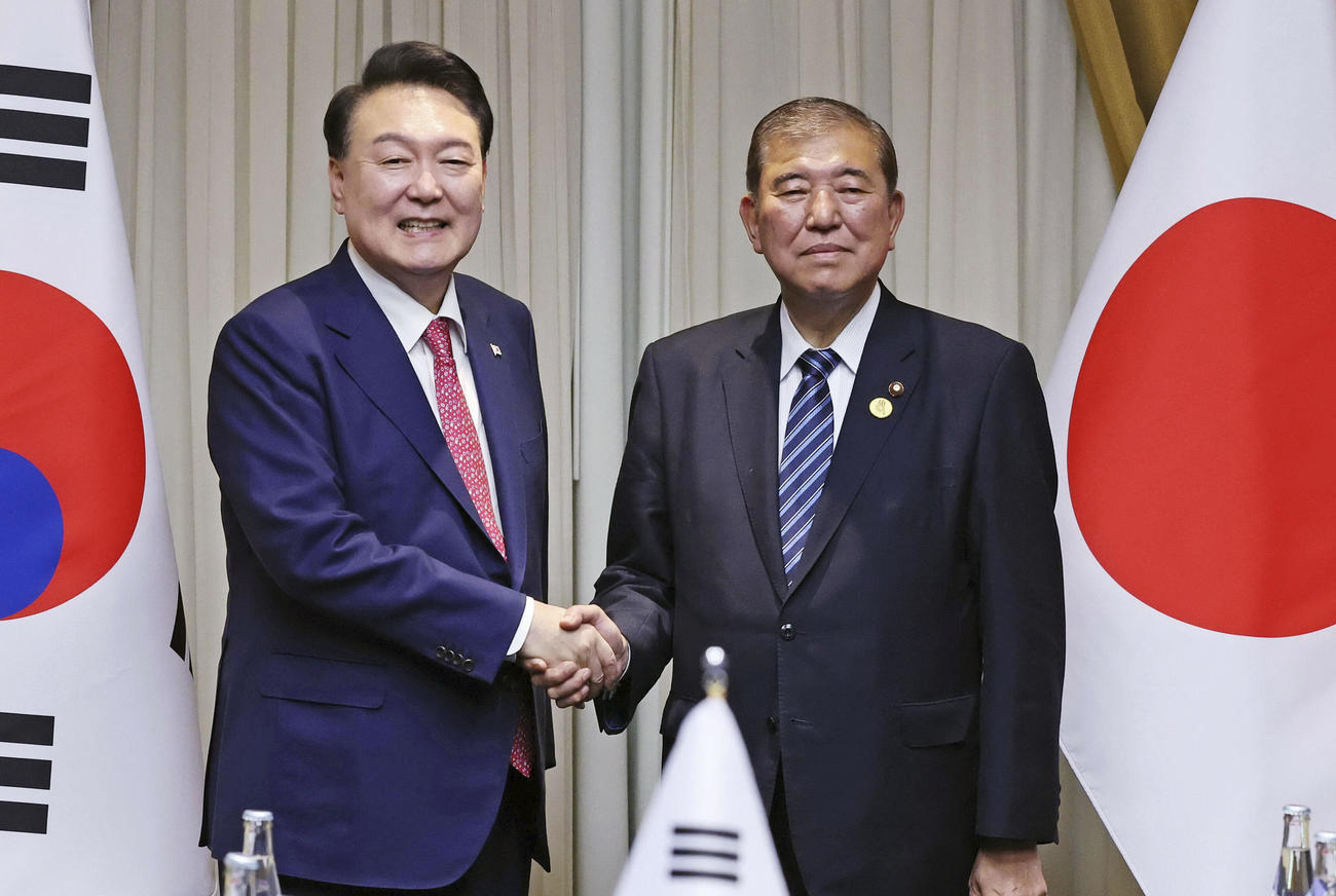 会談を前に握手する石破首相（右）と韓国の尹錫悦大統領（共同）
