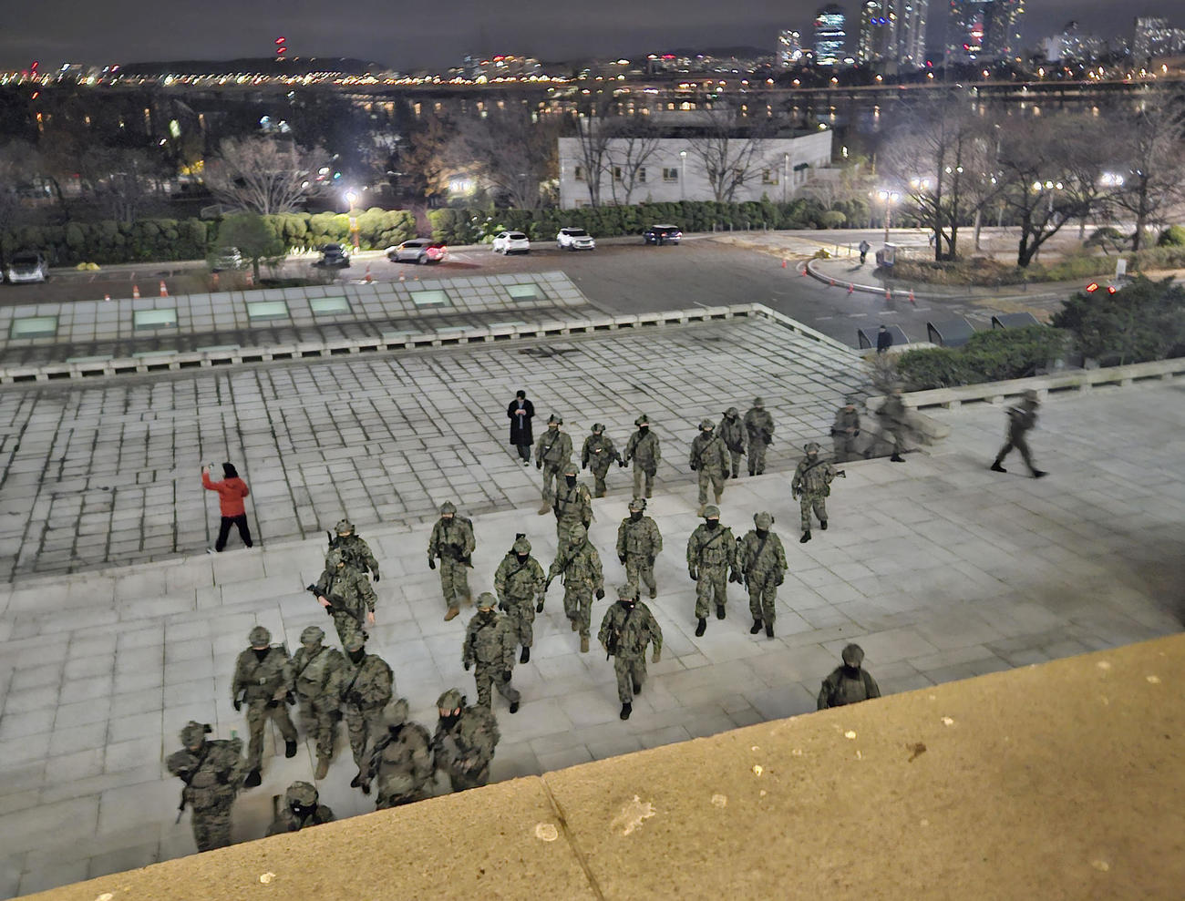 4日、韓国国会敷地内で出入り口に向かう軍人たち＝ソウル（共同）