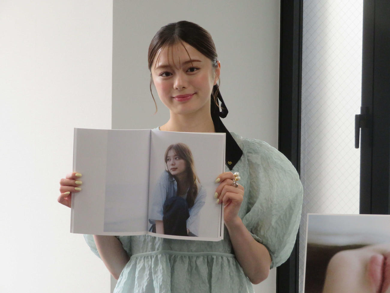 ファーストフォトブック「透」発売記念取材会でお気に入りの写真を見せ、笑顔の紺野彩夏（撮影・村上幸将）