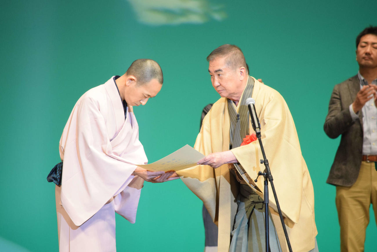 第16代社会人落語王者に輝いた宮永真也（高座名・呆っ人）さんに表彰状を渡す桂文枝（右）（撮影・阪口孝志）