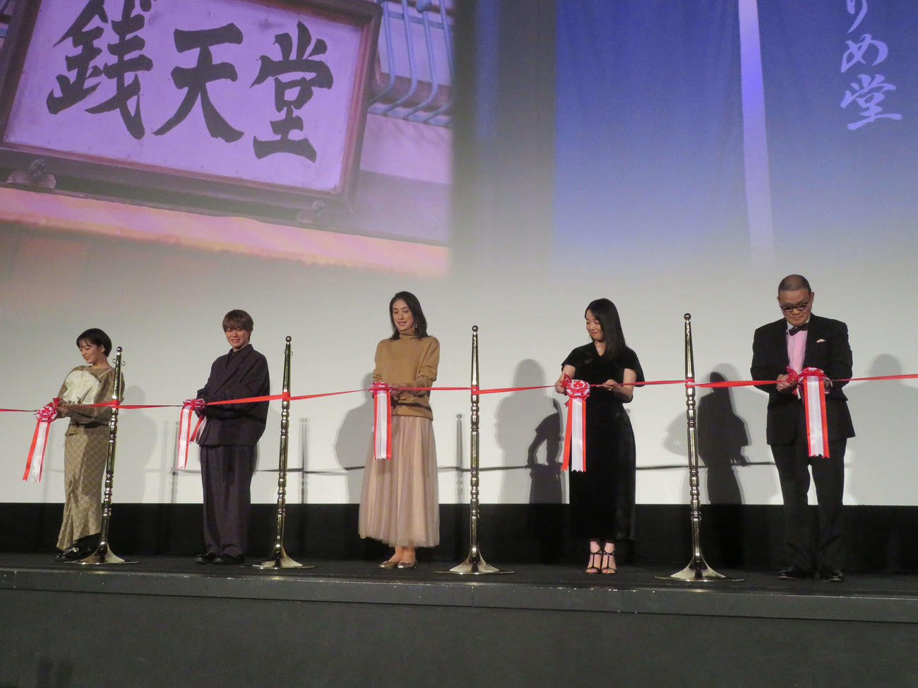 映画「ふしぎ駄菓子屋銭天堂」初日舞台あいさつに登壇し、テープカットする、左から伊原六花、なにわ男子の大橋和也、天海祐希、上白石萌音、中田秀夫監督（撮影・村上幸将）