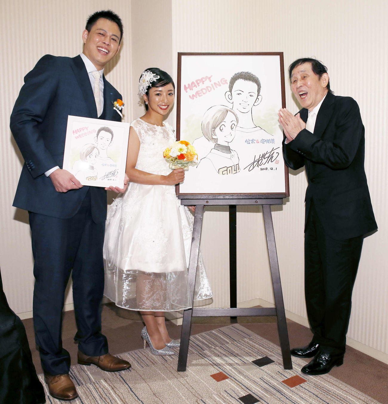 片岡安祐美、小林公太氏結婚披露宴　漫画家あだち充氏から贈られたサプライズボードの横で笑顔を見せる、左から元DeNA投手の小林公太氏、茨城ゴールデンゴールズ（GG）の片岡安祐美、萩本欽一＝2018年12月1日　
