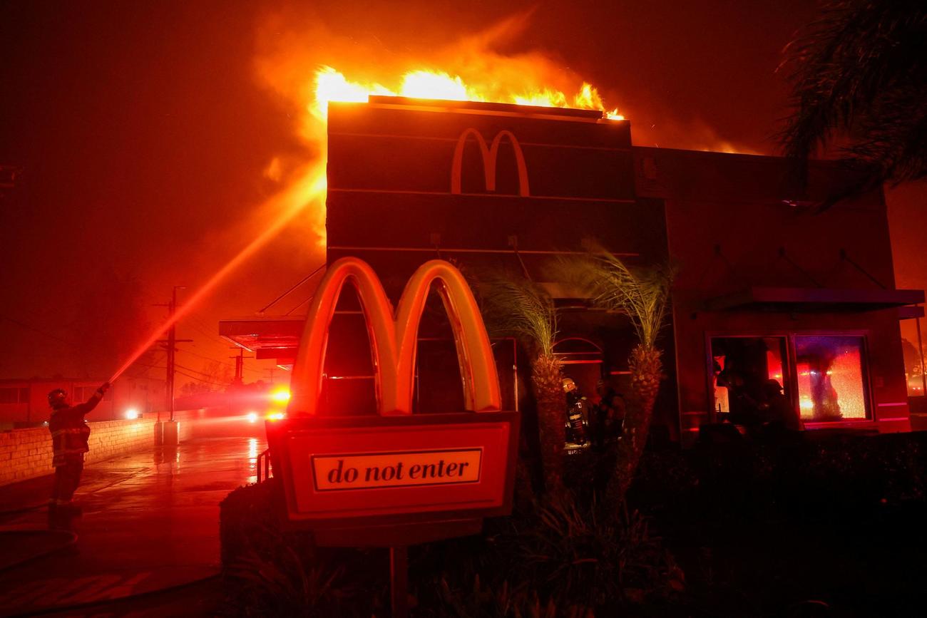 マクドナルドに燃え移った火を消そうとする消防士（ロイター）
