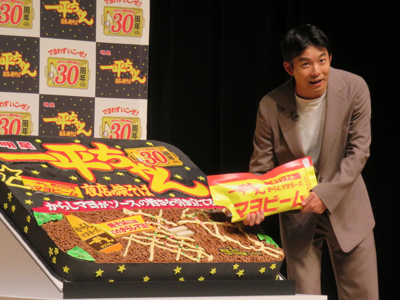 「明星　一平ちゃん夜店の焼そば」発売30周年記念発表会で、巨大ケーキにマヨビームで生クリームをかける仲野太賀