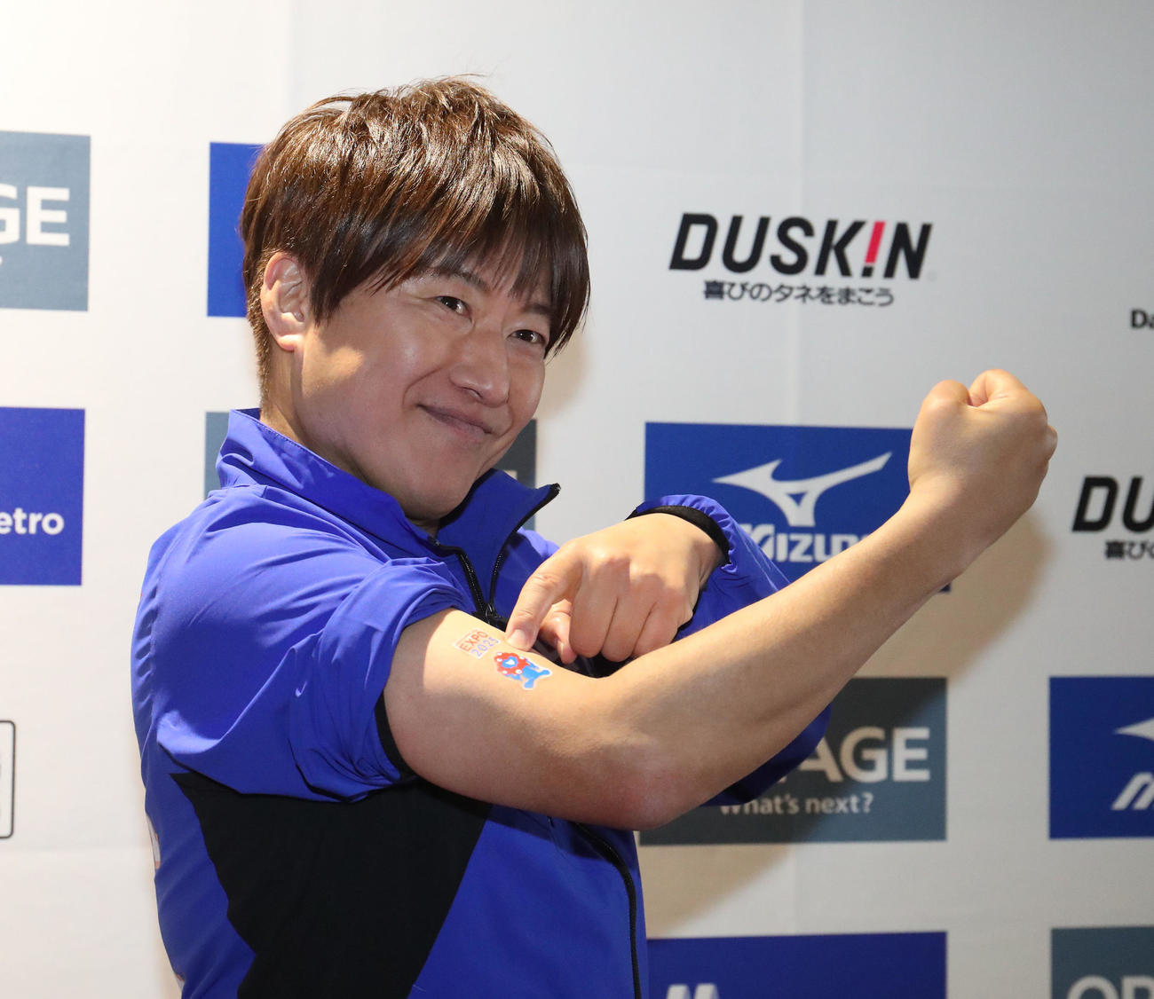 大阪マラソンを走り終えて右腕のミャクミャクのシールを見せる小渕健太郎（撮影・白石智彦）