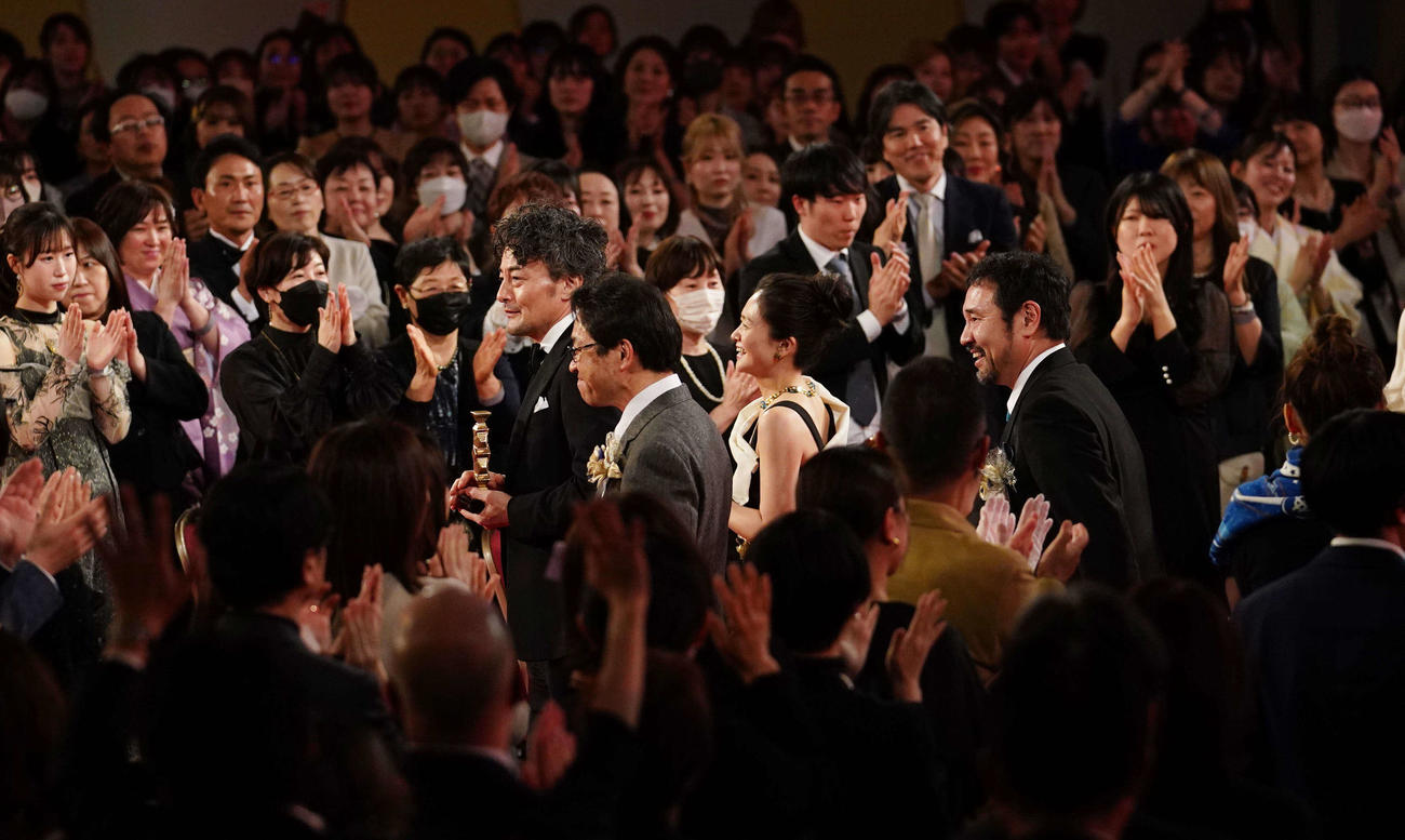 最優秀作品賞に選ばれ拍手を受けながら降壇する映画「侍タイムスリッパー」の安田淳一監督（右）ら関係者たち（撮影・横山健太）