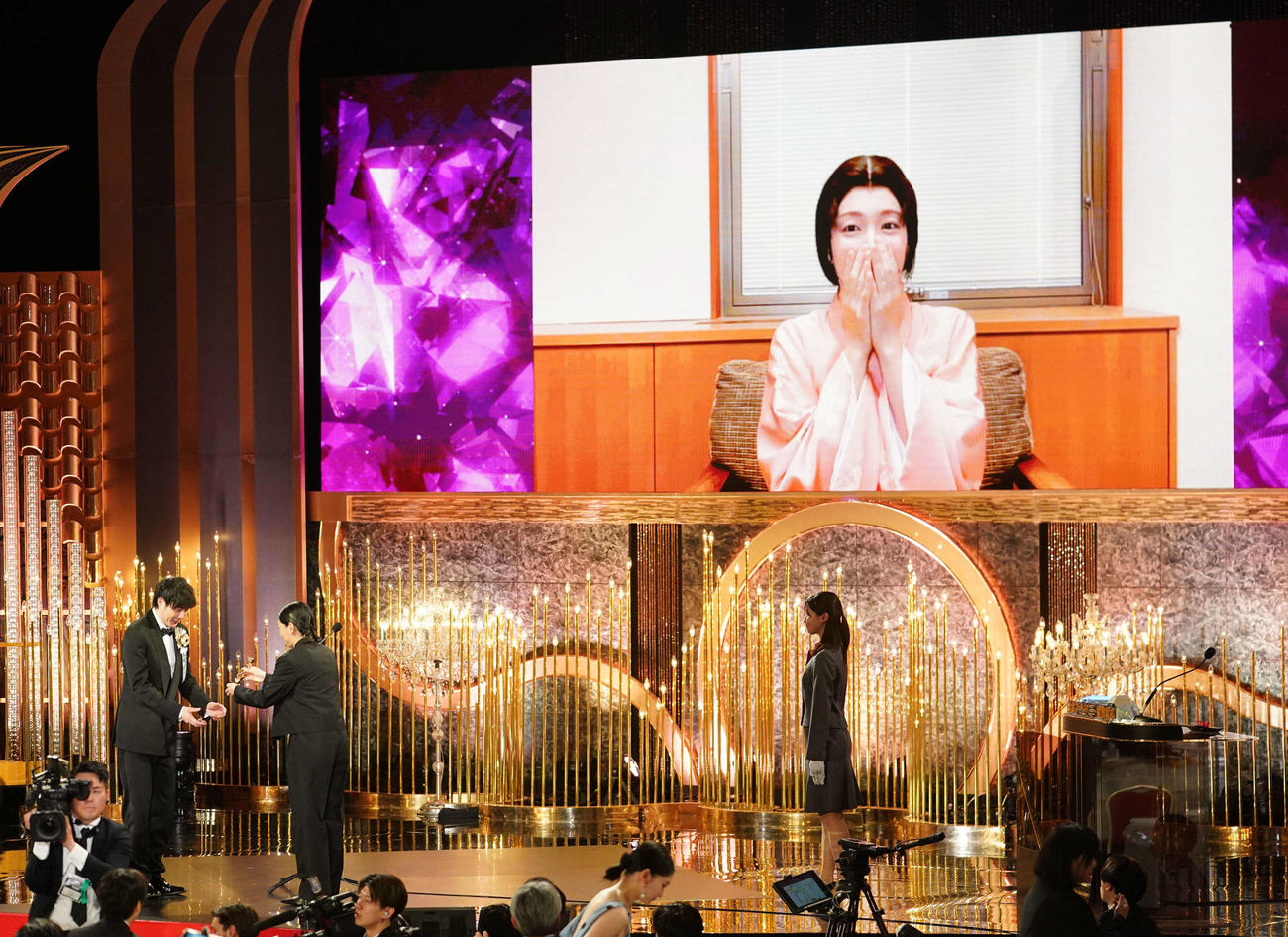 最優秀助演女優賞に選ばれ代理でトロフィーを受け取る藤井道人監督（手前左）とリモート出演で驚いた様子の吉岡里帆（撮影・横山健太）