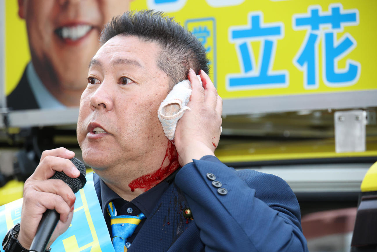 路上で暴漢に襲われ出血した状態でマイクで襲われた状況などを話す立花孝志氏（撮影・中島郁夫）