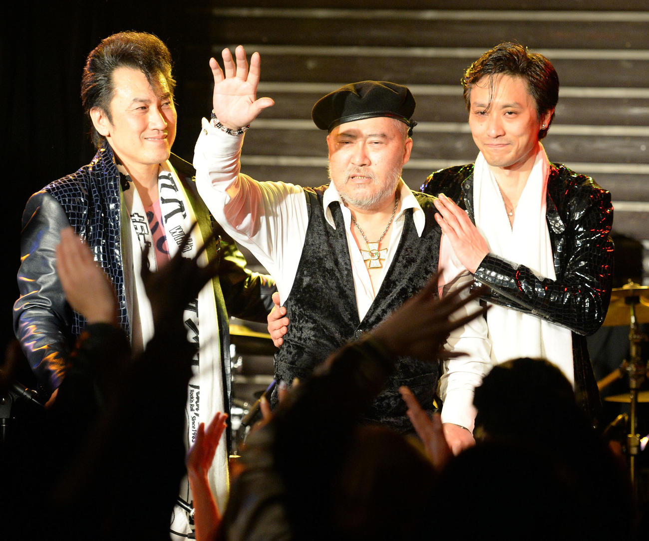 復活ライブを終え観客の声援に応えながらステージを後にするジョニー大倉。右は長男のケンイチ大倉、左は坂本つとむ（2014年4月撮影）