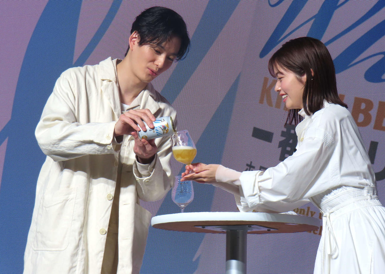 「一番搾り　ホワイトビール」を注ぎ合う岡田将生（左）と小芝風花