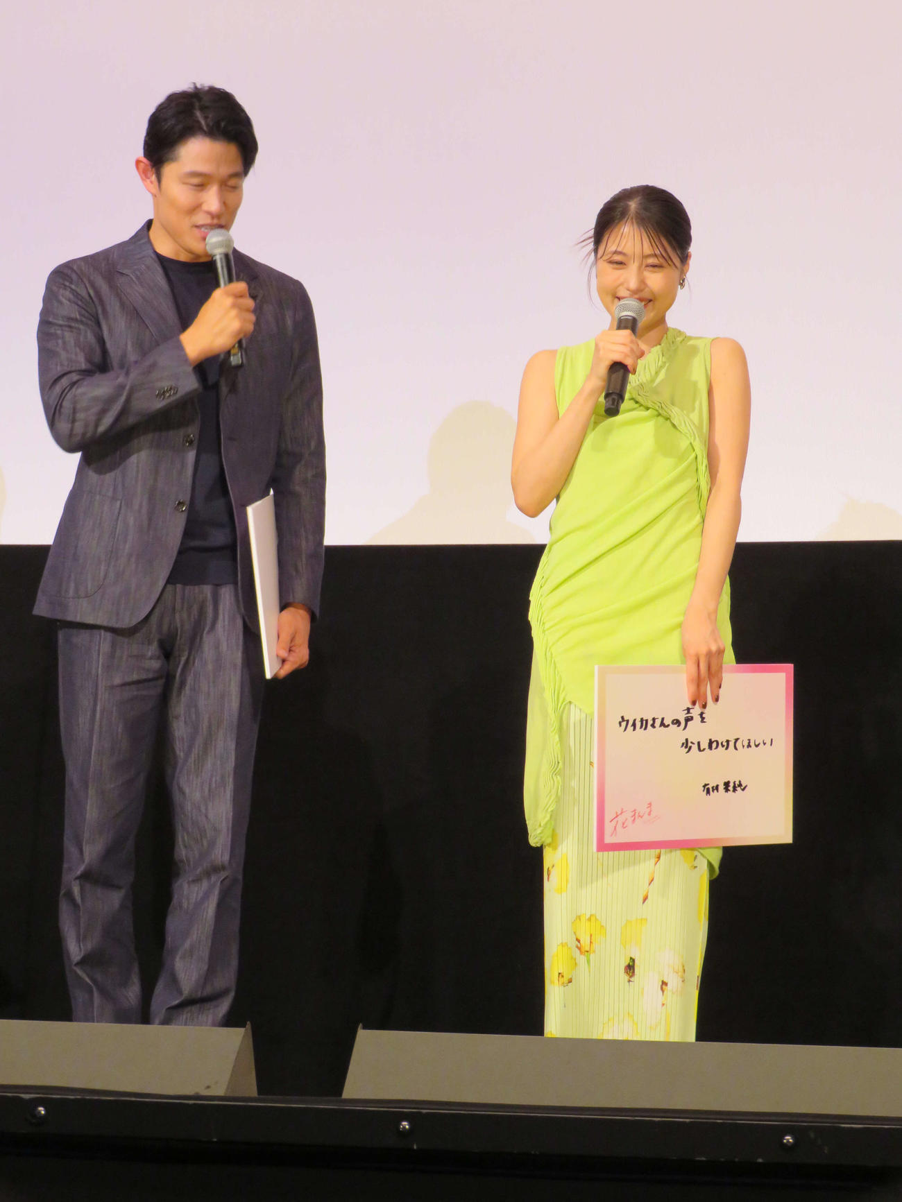 映画「花まんま」初日舞台あいさつに登壇した鈴木亮平と「ウイカさんの声を少しわけてほしい」と書いたフリップを手に笑顔の有村架純（撮影・村上幸将）