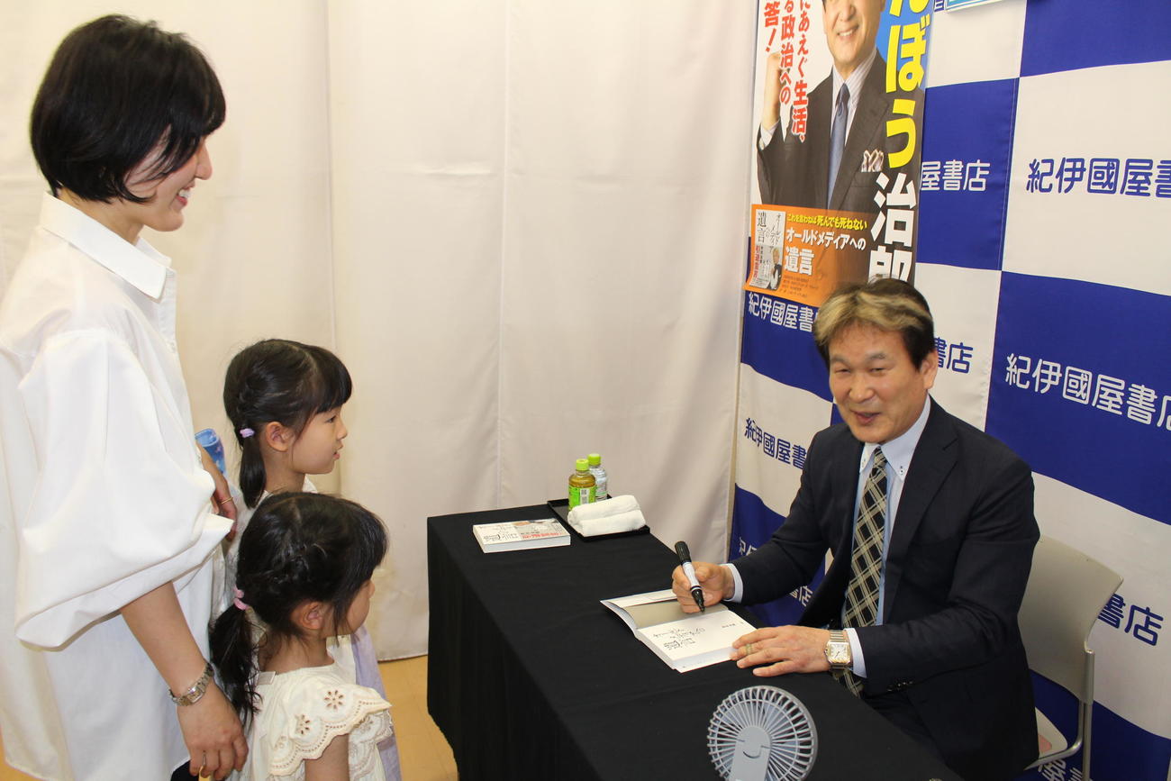 新著にサインする辛坊治郎氏