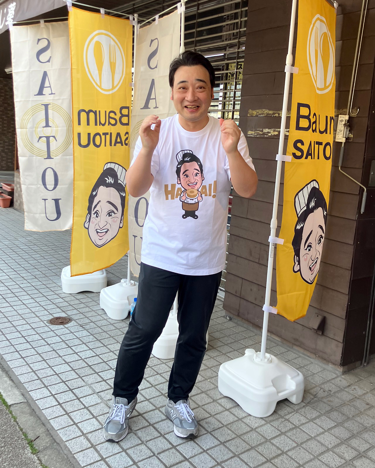 店頭に立ち、笑顔でポーズを決める斉藤慎二被告（2025年4月撮影）