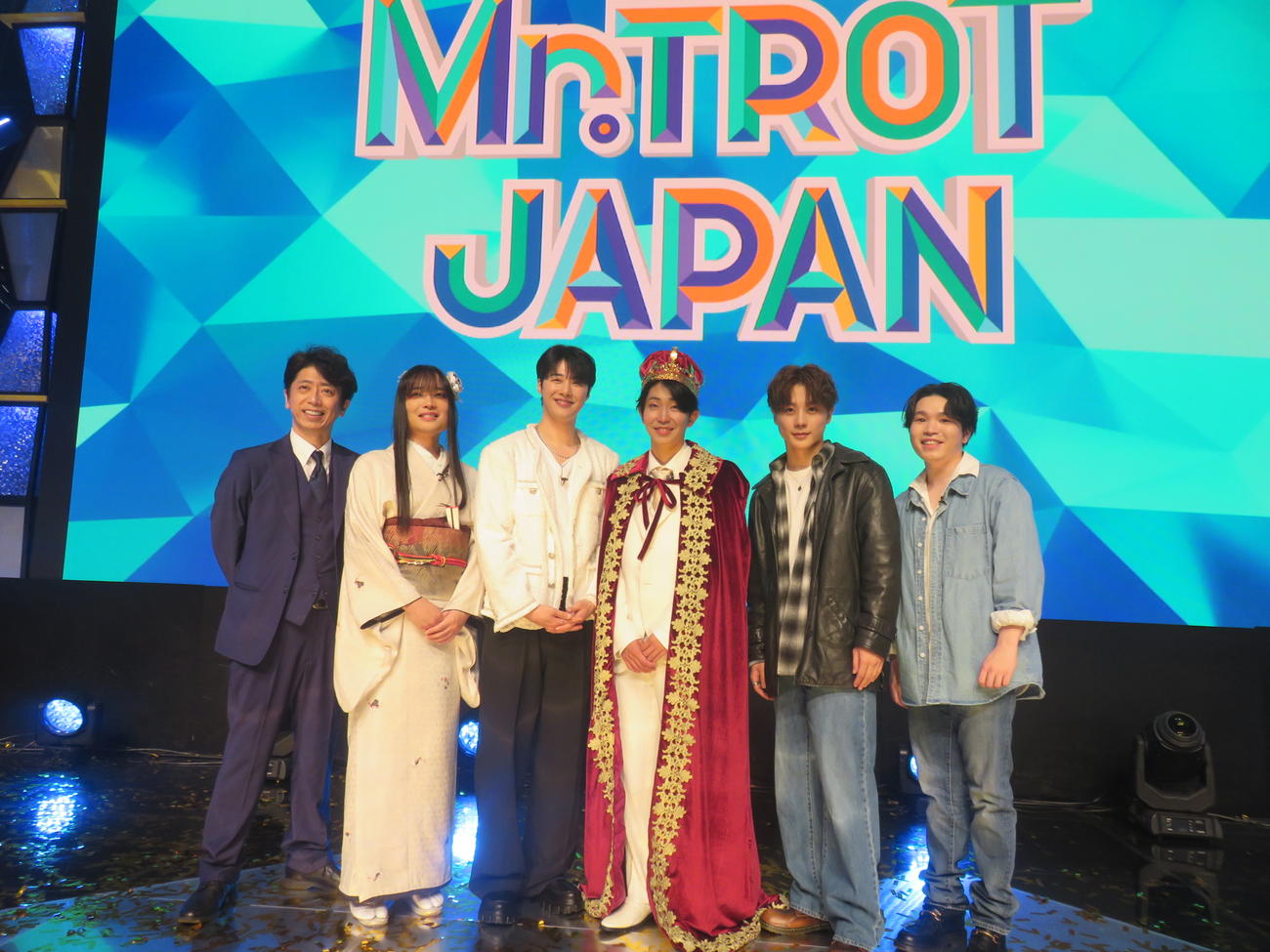 「ミスタートロット　ジャパン　ファイナル」で優勝した島憂樹さん（左から4人目）。左からMCの後藤輝基、ファイナリストの風水ノ里恒彦さん、ジュノさん、1人おいて橋詰昌慧さん、牛島隆太さん