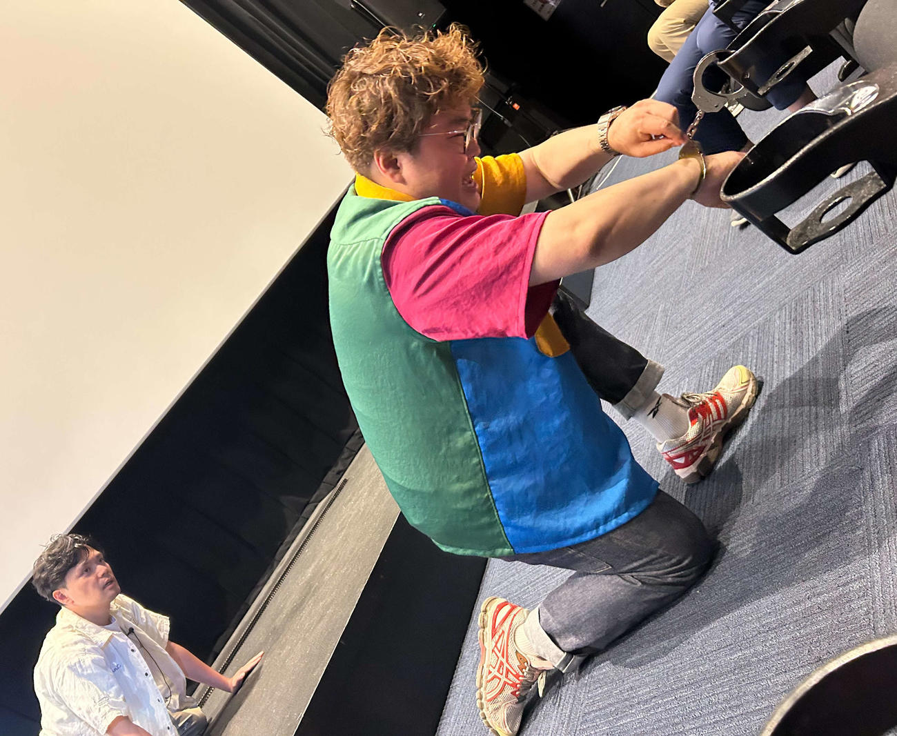 「マユリカの東京友錠生活　ディレクターズ・カット版」公開記念舞台あいさつ＆特別企画付き上映イベントに出席し、阪本（左）によって映画館のドリンクホルダーにつながれ、脱出をはかる中谷（撮影・松尾幸之介）
