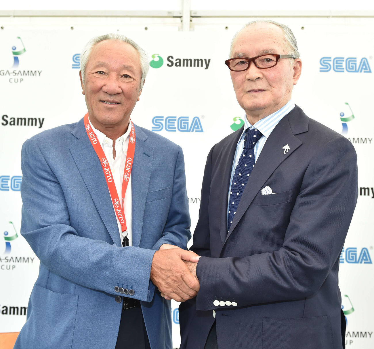 記者会見で握手する大会名誉会長の長嶋茂雄氏（右）とJGTO青木功会長（撮影・鈴木みどり）