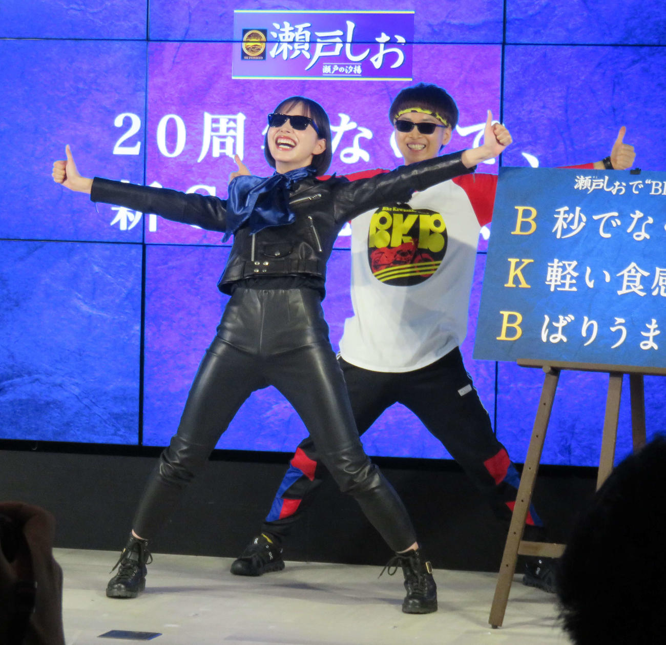 「栗山米菓　瀬戸しお　♯20周年なので　新CM発表会」で「BKB」作文に挑戦する井桁弘恵（前）とバイク川崎バイク