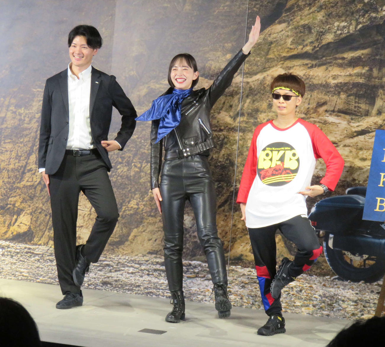 「栗山米菓　瀬戸しお　♯20周年なので　新CM発表会」で「BKB」ポーズをする井桁弘恵（中央）とバイク川崎バイク（右）
