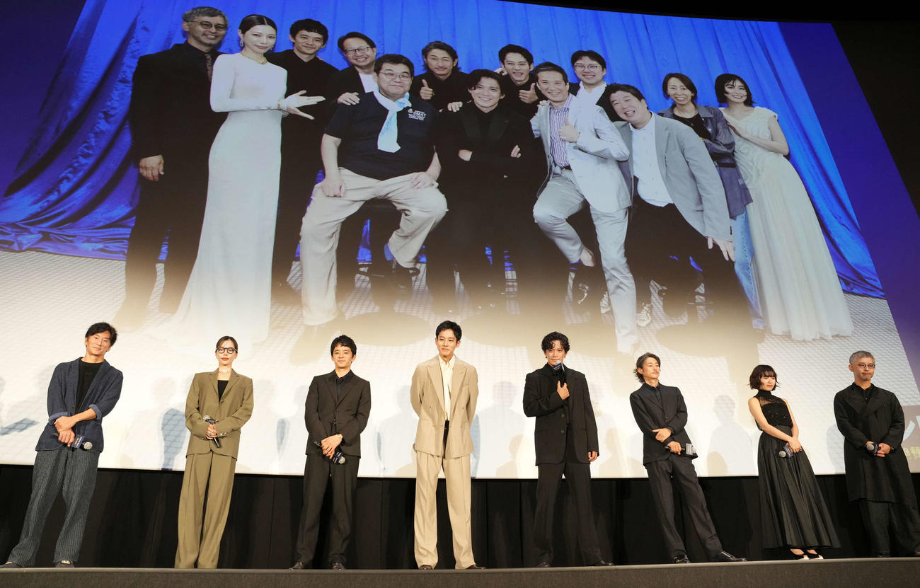 映画「フロントライン」初日舞台あいさつで、モデルになった人たちとの写真を見て笑顔の出演者たち。左から増本淳プロデューサー、桜井ユキ、池松壮亮、松坂桃李、小栗旬、窪塚洋介、森七菜、関根光才監督（撮影・鈴木みどり）