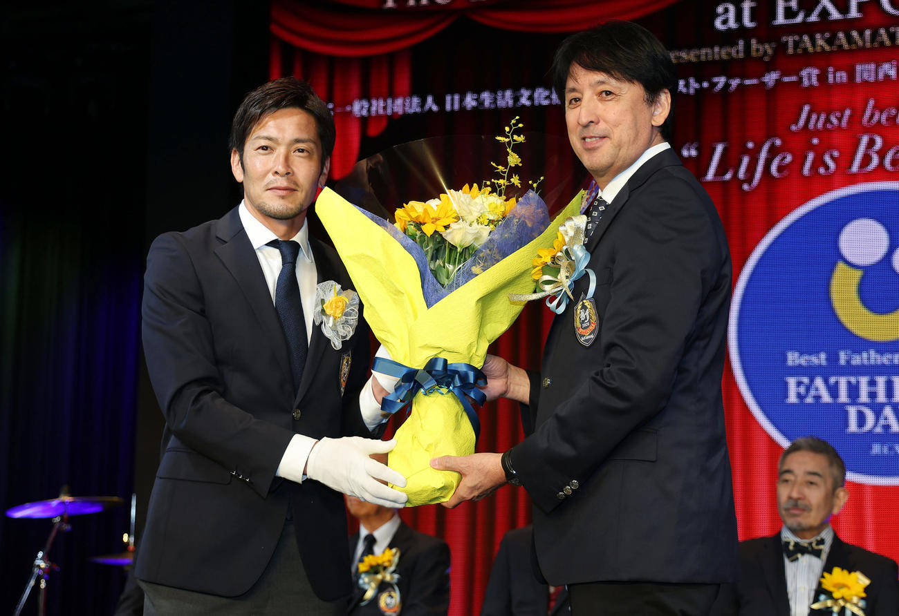 「2025年度　第18回ベスト・ファーザー賞in関西」の授賞式で花束を受け取る星野伸之氏。左はプレゼンターを務めた加地亮氏（撮影・前田充）