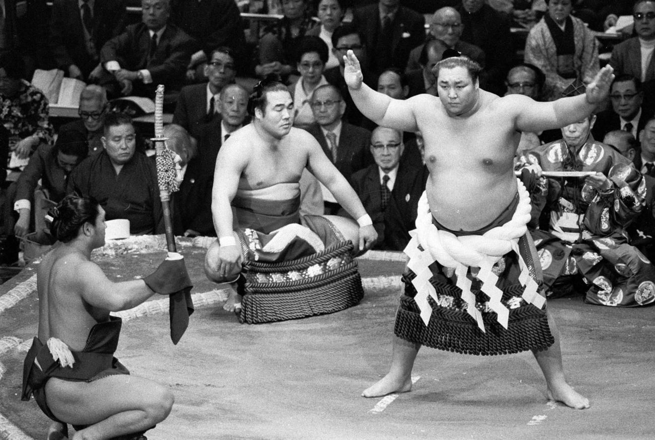 75年初場所初日、横綱北の湖の土俵入りで太刀持ちを務める増位山（左）。露払いは栃東、行司は26代木村庄之助（1975年1月）