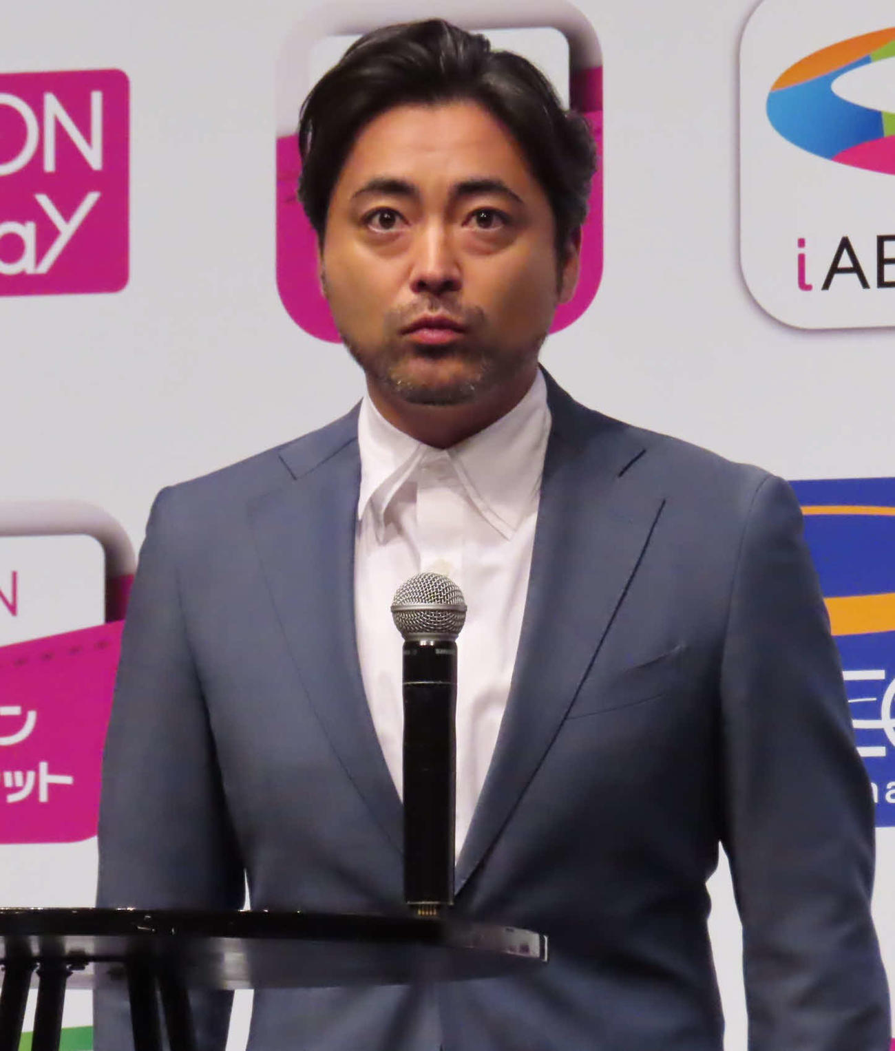「AEON Pay」新CM発表会で、机にマイクを立てて話す山田孝之