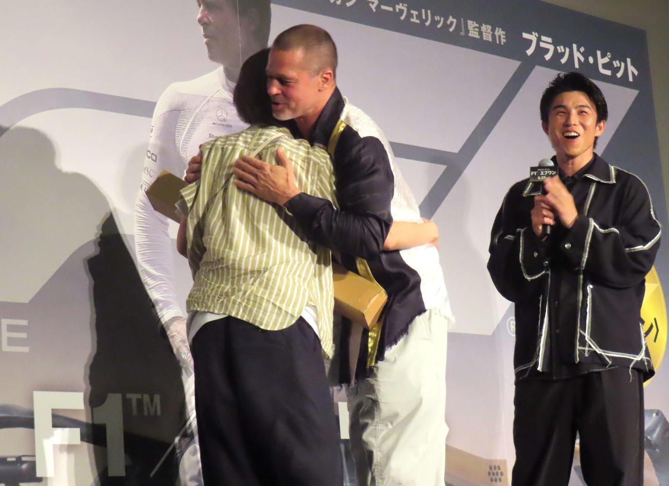 映画「F1／エフワン」来日舞台あいさつで抽選に当たったファンをハグするブラッド・ピット（左）と見守る中尾明慶