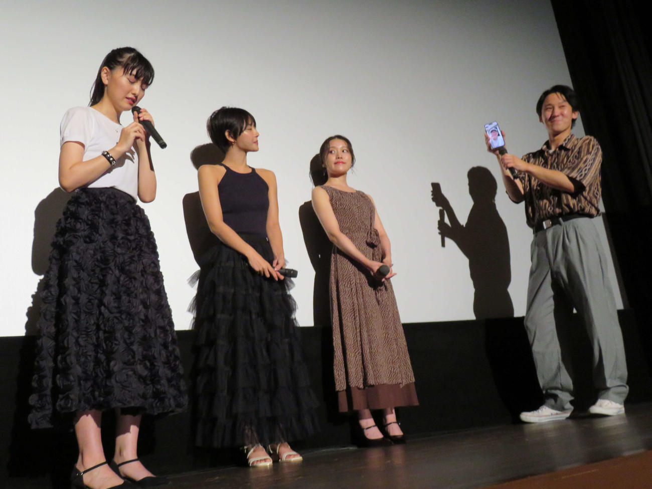 映画「架空書影。」初日舞台あいさつで、笹生翔也（右）が手にしたスマートフォンの中に映る、長谷川朋史監督にお礼し、涙ぐむ峰平朔良（左）（撮影・村上幸将）
