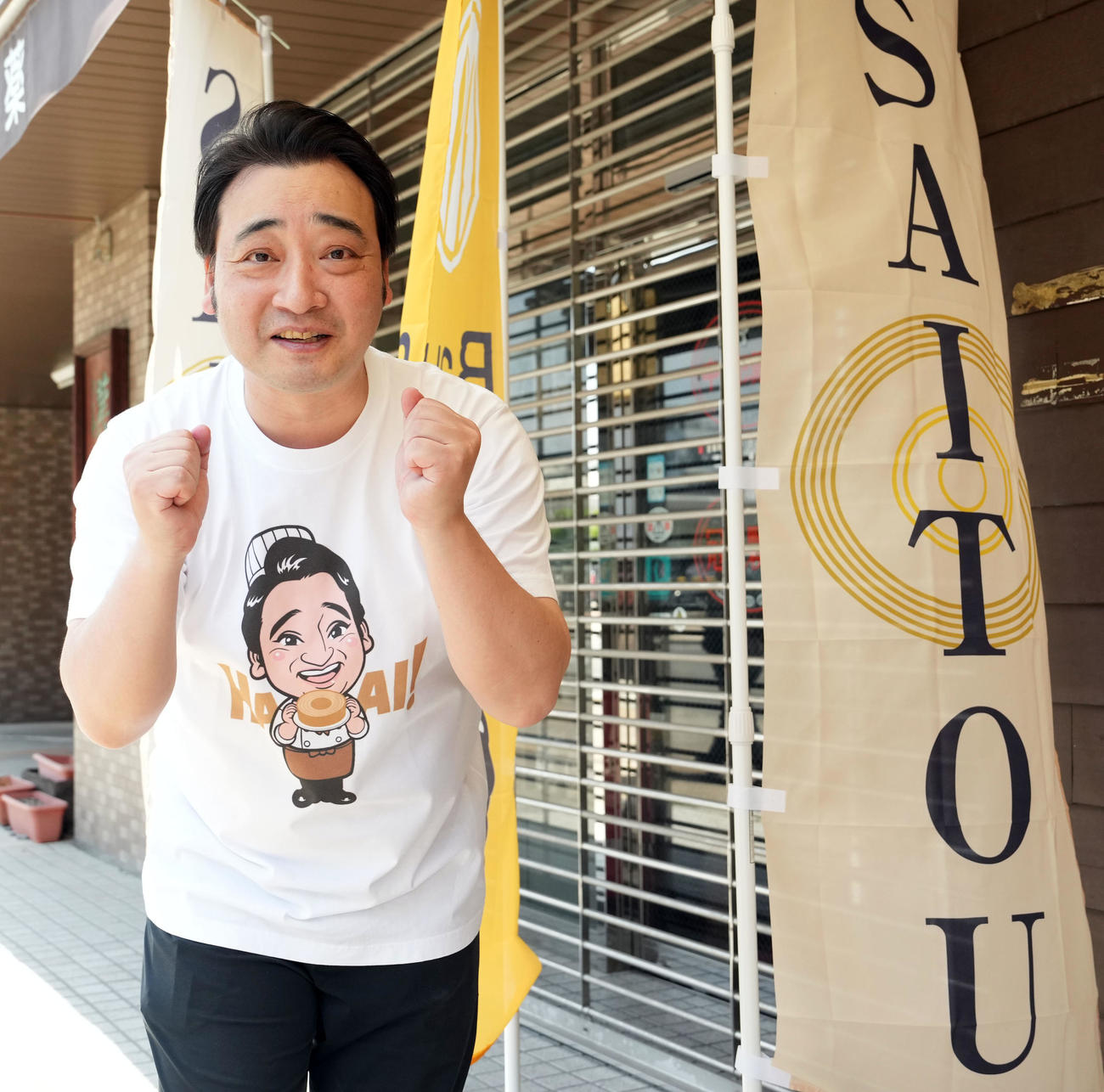 店頭に立ち、サービスでポーズを決める斉藤慎二被告（2025年4月撮影）