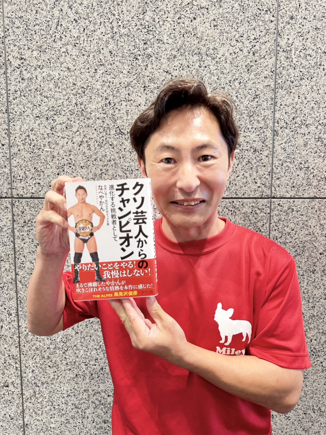 著書「クソ芸人からのチャンピオン－進化する挑戦者として」を手にするなべやかん