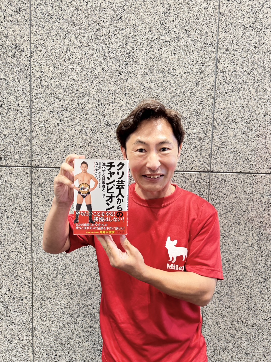 著書「クソ芸人からのチャンピオン－進化する挑戦者として」を手にするなべやかん