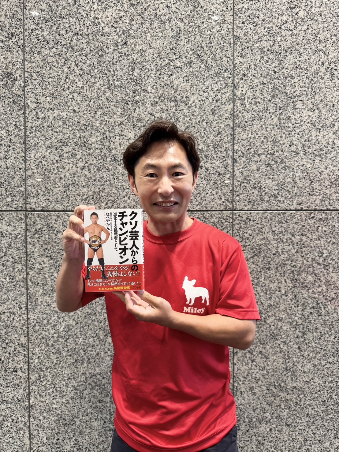 著書「クソ芸人からのチャンピオン－進化する挑戦者として」を手にするなべやかん