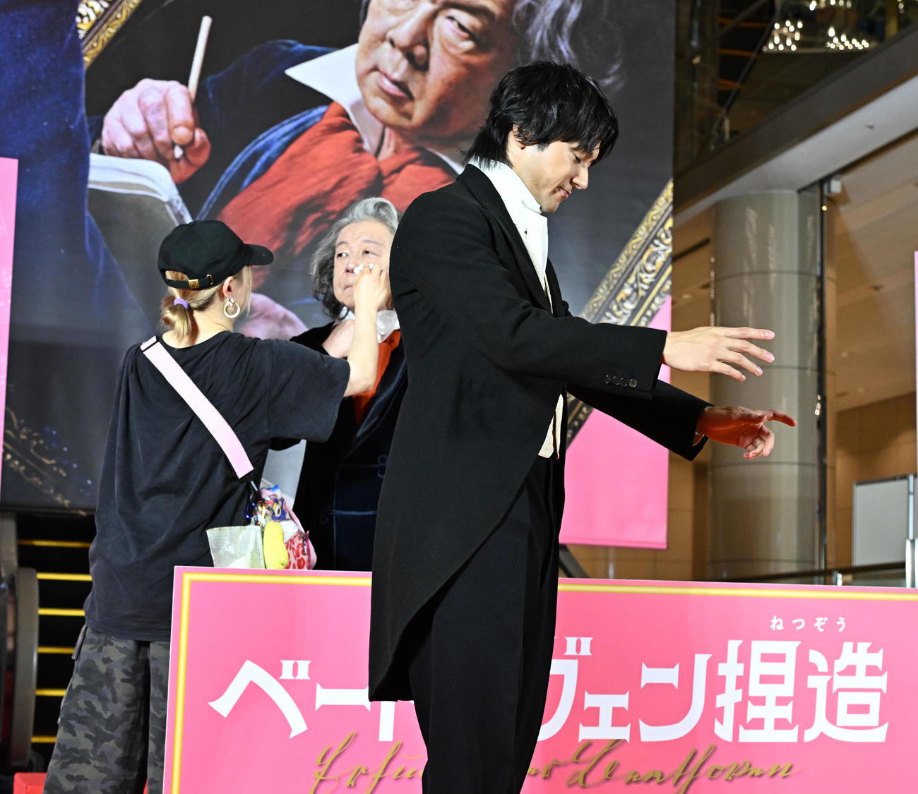 映画「ベートーヴェン捏造」のレッドカーペットセレモニーで、古田新太（後方）の化粧直し中に指揮者のジェスチャーで場を持たせる山田裕貴（撮影・千葉一成）