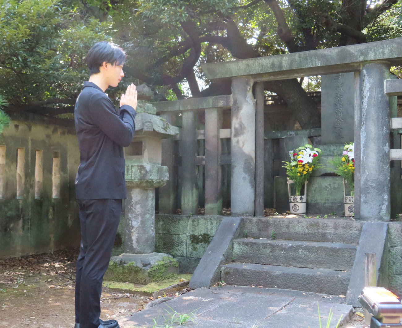 霊厳寺にある松平定信の墓石に手を合わせる井上祐貴（撮影・寺本吏輝）