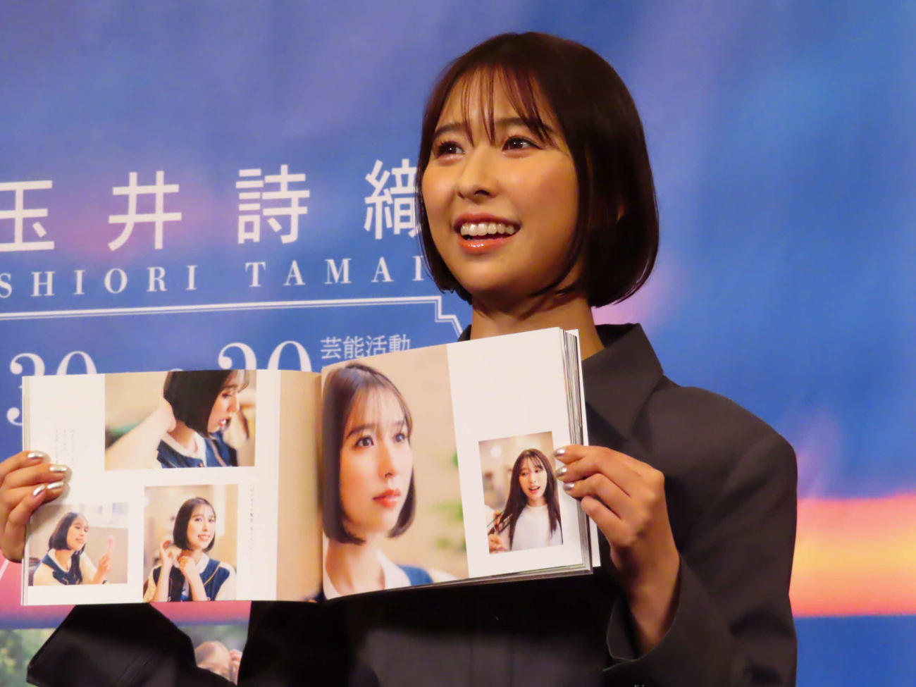玉井詩織1st写真集「たまゆら」ストーリー写真集「しおどき」発売記念イベントで、「しおどき」のお気に入りカットを見せる玉井詩織