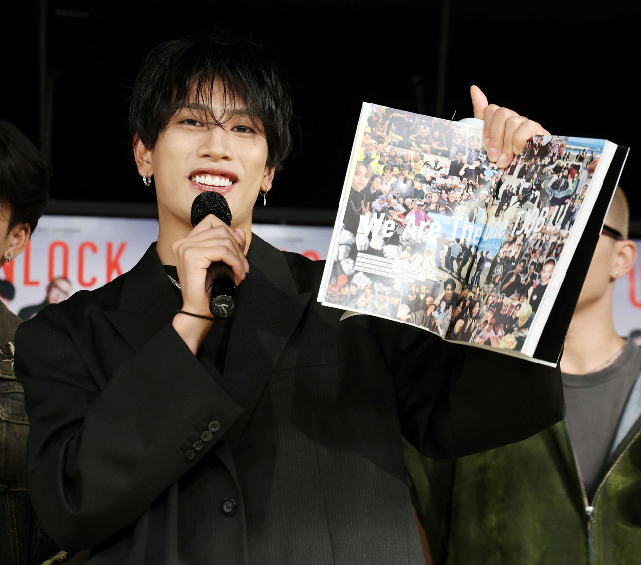 「THE JET BOY BANGERZ OFFICIAL ARTIST BOOK UNLOCK」発売記念イベントに登壇し、お勧めのページを見せるAERON（撮影・山本朝陽）