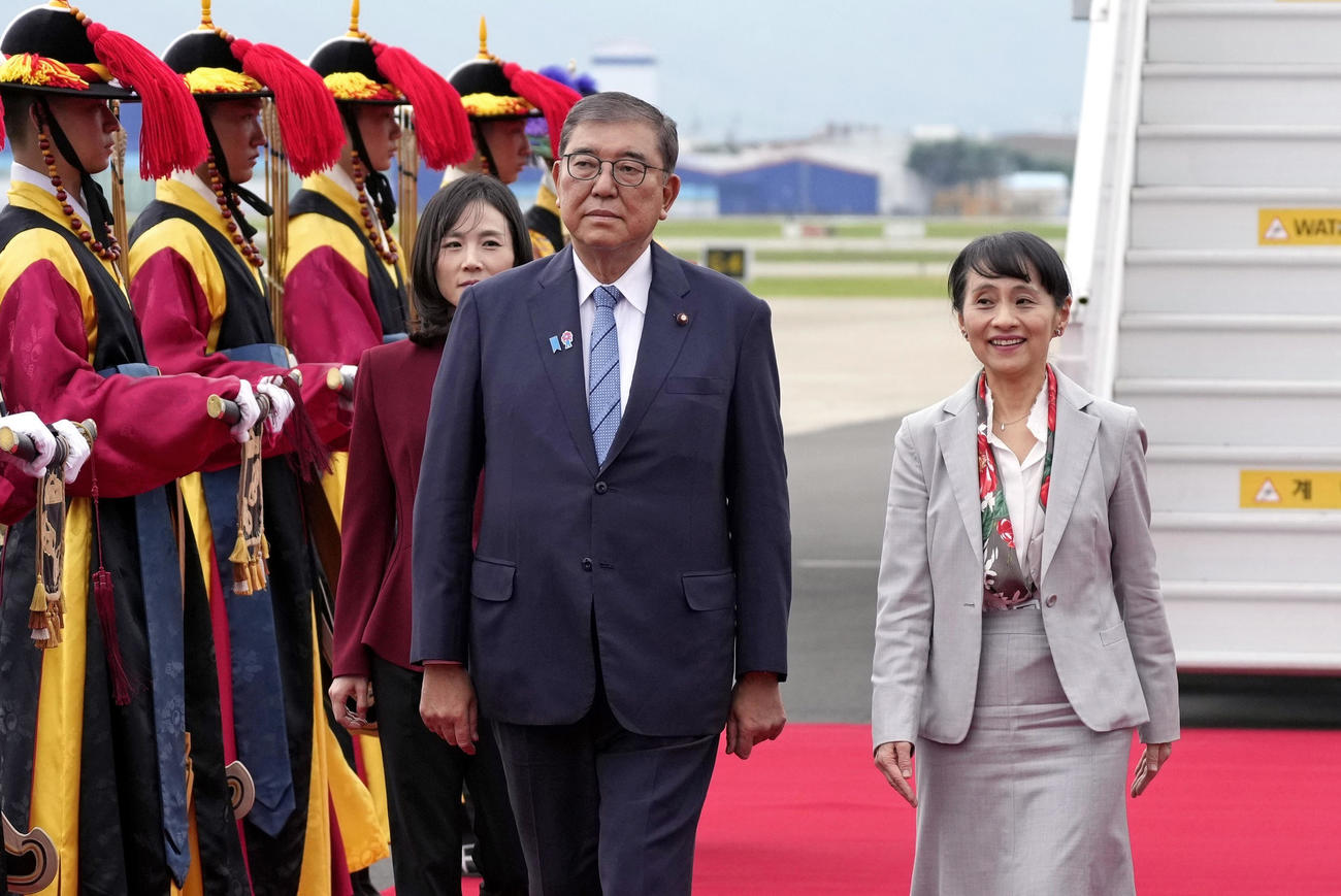 韓国・釜山の金海国際空港に到着し、出迎えを受ける石破首相。右は妻の佳子さん（共同）