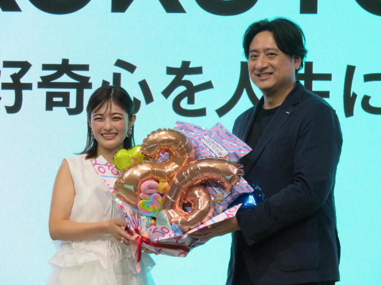 「コクヨ　リブランディング発表会　映画完成披露会」でポップコーンブーケで誕生日を祝われる井上咲楽（左）。右はコクヨの黒田英邦社長