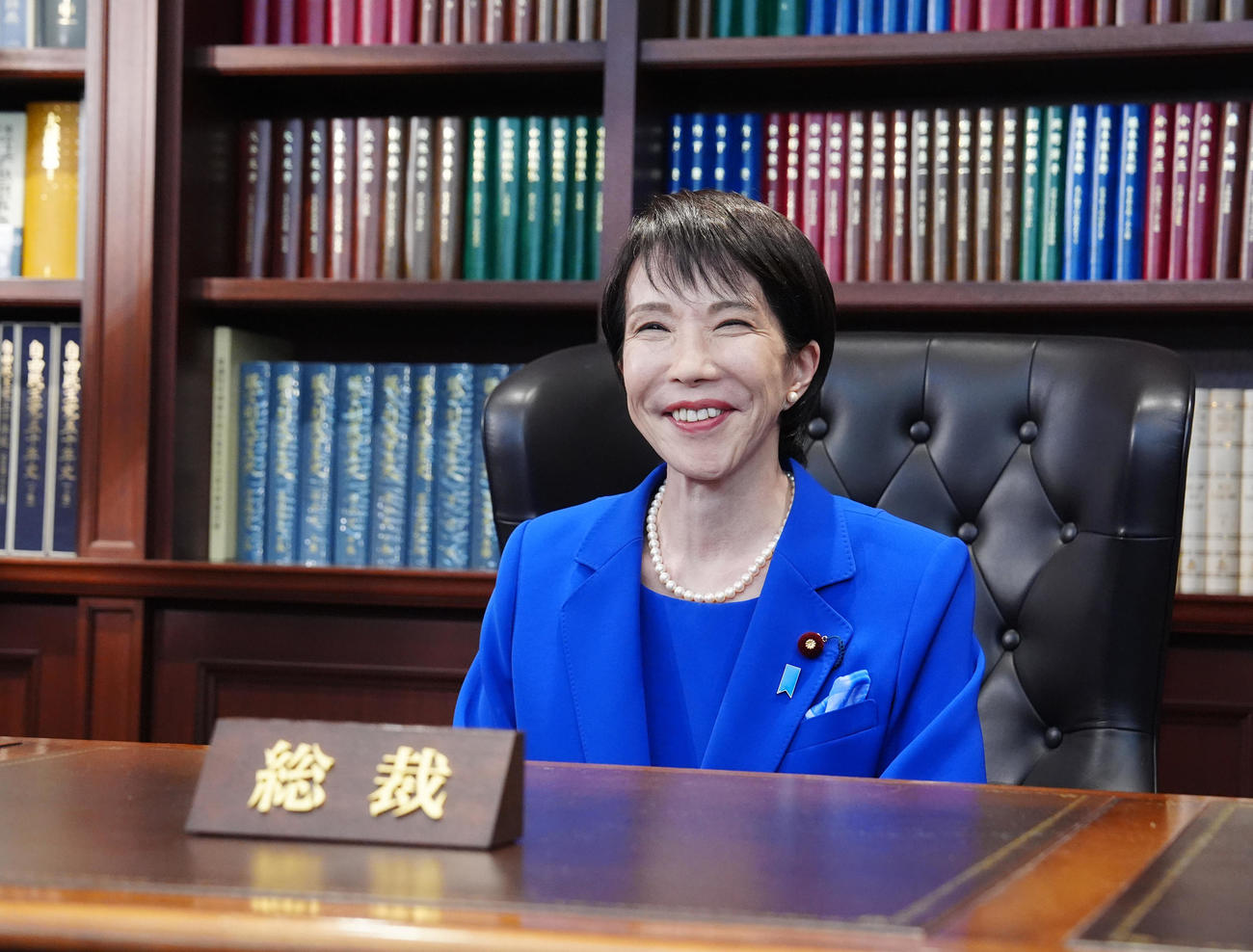 総裁の椅子に座り、笑顔を見せる自民党新総裁の高市早苗氏（2025年10月4日撮影）