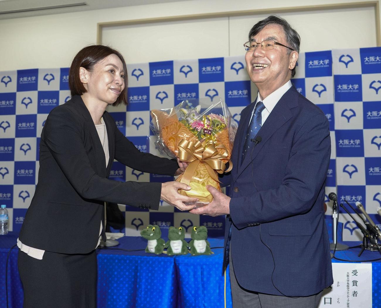 ノーベル生理学・医学賞の受賞が決まり、記者会見場で花束を受け取る大阪大の坂口志文特任教授（右）＝6日午後8時3分、大阪府吹田市（共同）