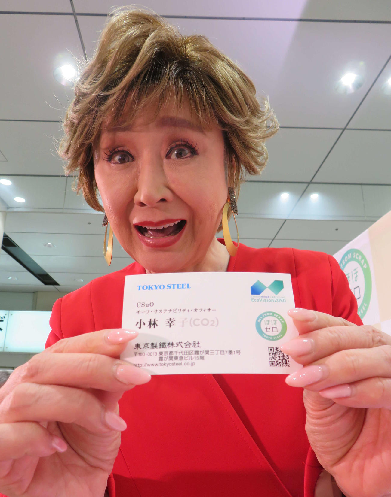 電炉鉄鋼メーカー「東京製鐵」の「ほぼゼロ」キャンペーンで作った名詞を差し出す小林幸子
