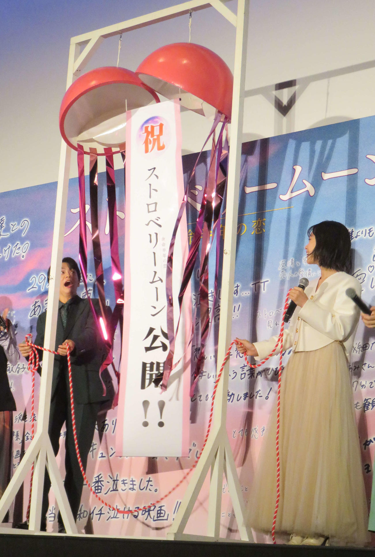映画「ストロベリームーン　余命半年の恋」初日舞台あいさつでくす玉を割った當真あみ（右）と齋藤潤