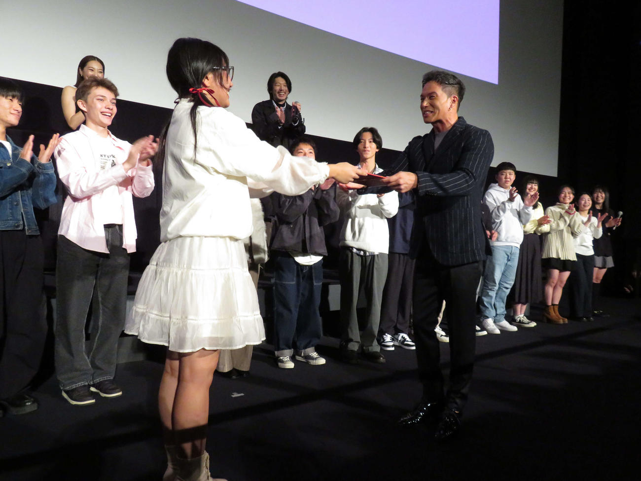 映画「おいしい給食　炎の修学旅行」大ヒット御礼舞台あいさつで忍川中の生徒を演じた一同と記念撮影する、後列左6人目から小堺一機、武田玲奈、市原隼人、栄信（撮影・村上幸将）