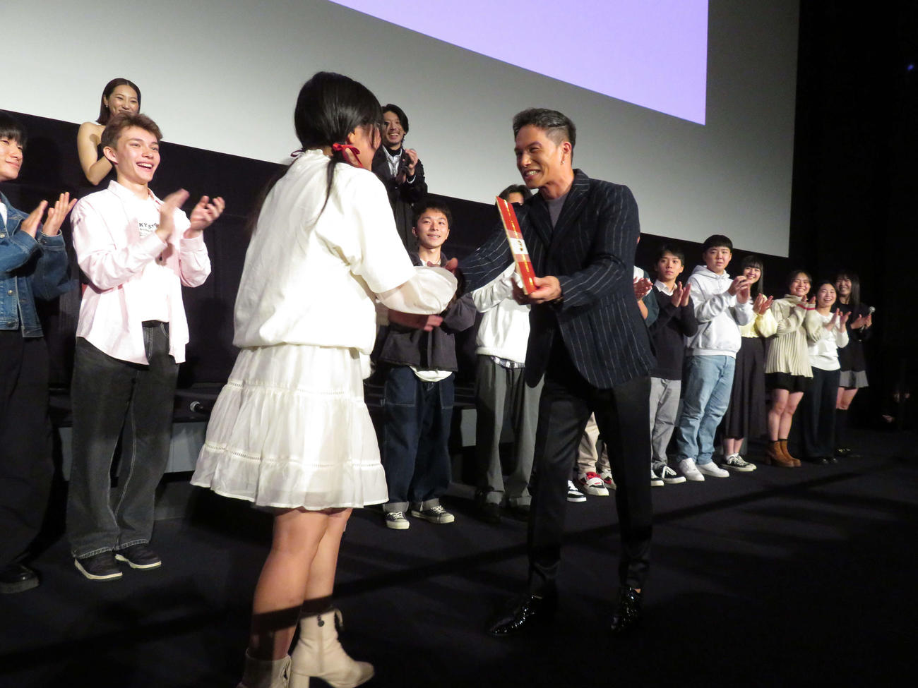 映画「おいしい給食　炎の修学旅行」大ヒット御礼舞台あいさつで忍川中の生徒を演じた一同と記念撮影する、後列左6人目から小堺一機、武田玲奈、市原隼人、栄信（撮影・村上幸将）