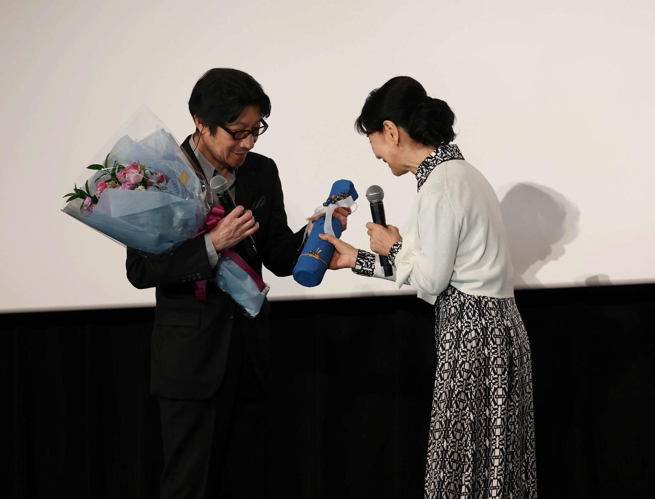 大ヒット御礼舞台あいさつで紫緩褒賞を受賞し、吉永小百合（右）からお祝いのワインをもらう阪本順治監督（撮影・増田悦実）