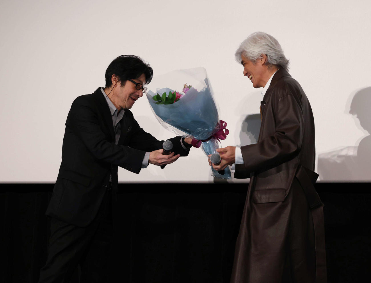 大ヒット御礼舞台あいさつで、紫緩褒賞を受賞し佐藤浩市（右）から花束をもらう阪本順治監督（撮影・増田悦実）