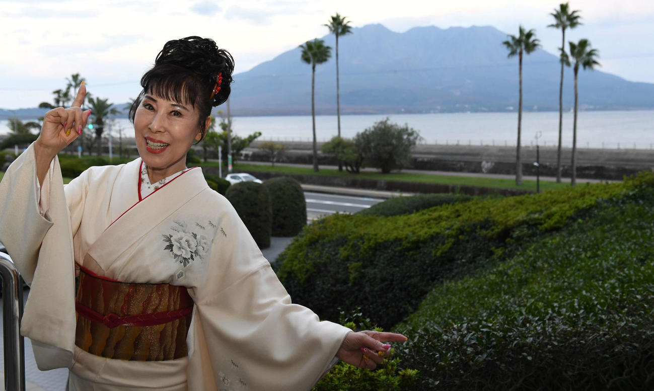 櫻島をバックにポーズを決める原田悠里