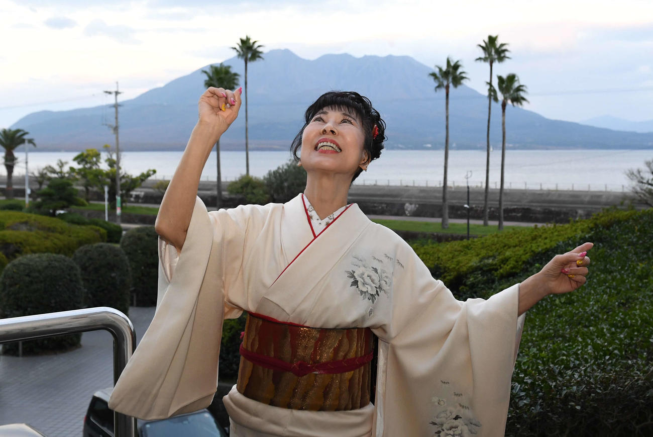 櫻島をバックにポーズを決める原田悠里