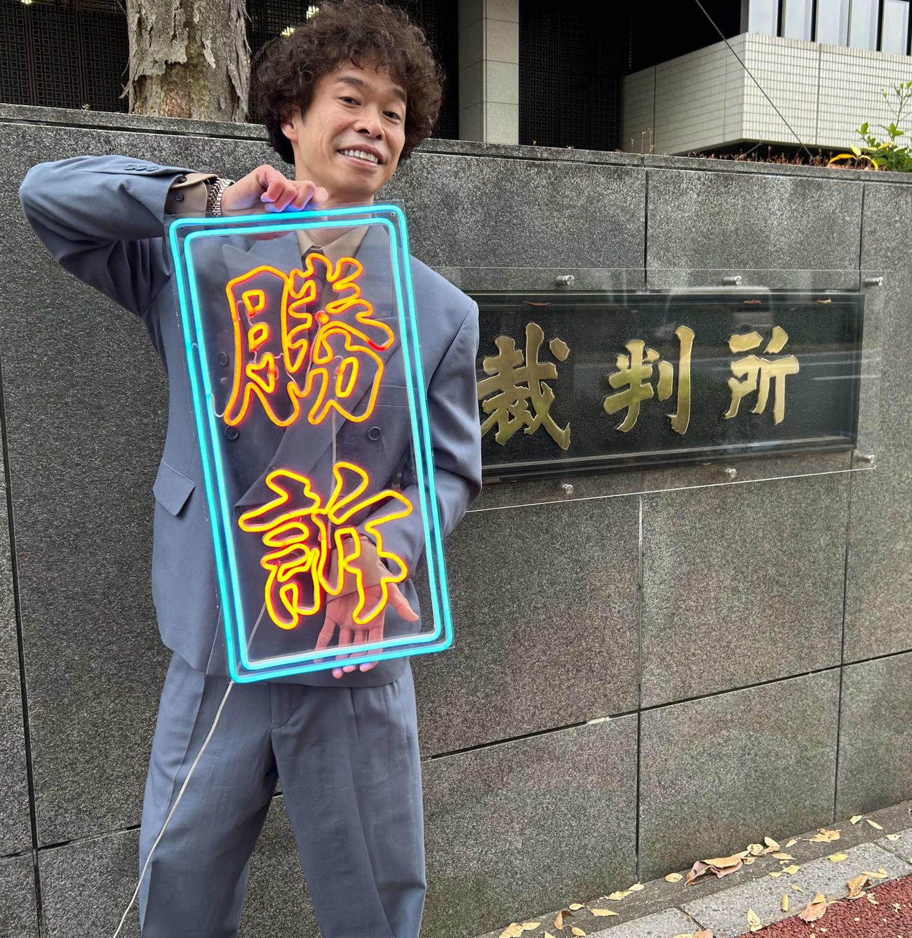 講談社との裁判の判決を受け、自作の「勝訴」のボードを掲げる渡邊センス（撮影・松尾幸之介）